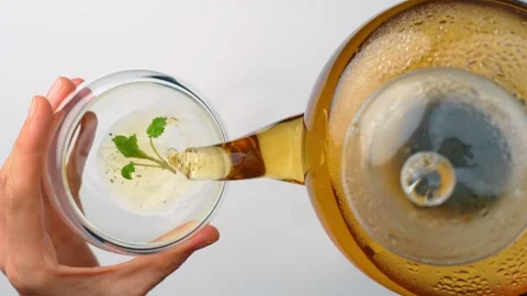 Top view of pouring hot tea into glass cup with lemon balm. Person holding Stock Footage 342976673