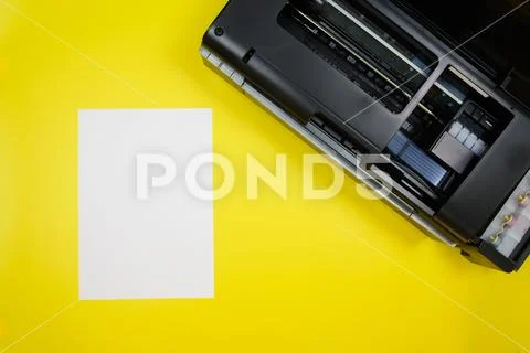 Top view of the printer and a blank sheet of a4 paper on a yellow ...