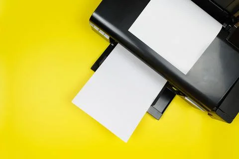 Top view of the printer and a blank sheet of a4 paper on a yellow background Stock Photos