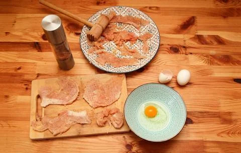 Top view of the process of preparing chicken schnitzels on a wooden table. .. Stock Photos