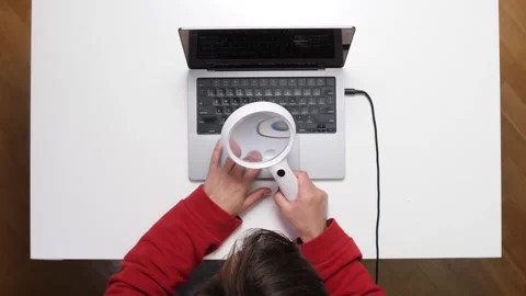Top view Programmer using magnifying glass while working on laptop Stock Footage 311202293