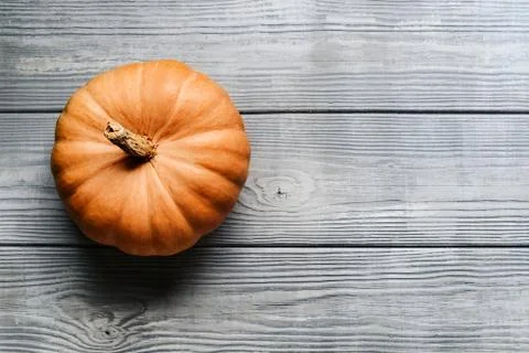 Top view of a pumpkin lying on a light wooden background with a copy space. Stock Photos