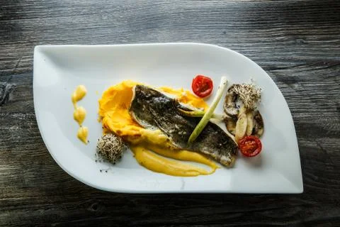 Top view on puree finely decorated with baked fish and vegetables Stock Photos