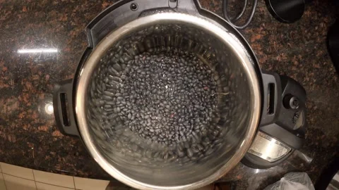 Top view of putting black beans and water to an instant pot for preparing a Video stock 321497971