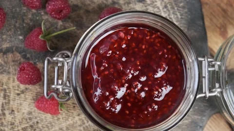 Top view of raspberry jam in a jar with fresh berries on wooden table Stock Footage 218458779