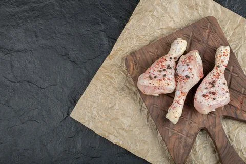 Top view raw chicken drumstick on wooden board Stock Photos