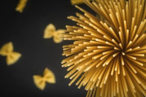 Top View of Raw Spaghetti Pasta Bundle and Farfalle on Black Background Stock Photos