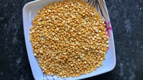 Top view of raw split chickpeas on a white square plate Stock Footage 328441262