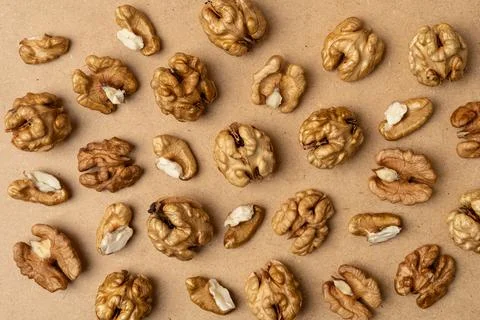 Top view of raw walnut kernels scattered on brown background. Natural healthy Stock Photos