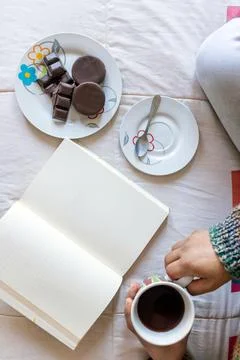 Top view reading a book with a cup of coffee and some chocolates Stock Photos
