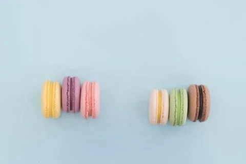 Top view of real colourful macarons on light blue background. Stock Photos