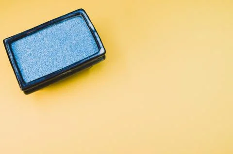 Top view of a rectangular box filled with small blue rocks on yellow backgrou 스톡 사진