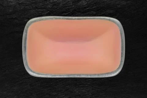 Top view of rectangular pink empty dish with silver edges on black stone back Foto stock