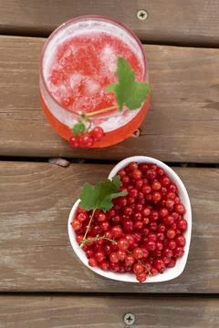 Top view red currant juice glass with bowl of fresh currants on wooden table Stock Photos