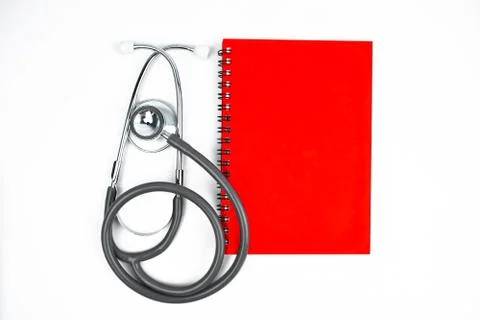 Top view of a red diary and a stethoscope placed beside one another on a whit Stock Photos