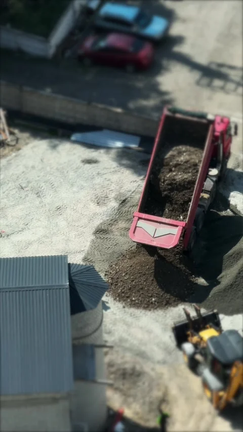 Top view of a red dump truck unloading a pile of gravel and dirt next to a .. Stock Footage 336794952
