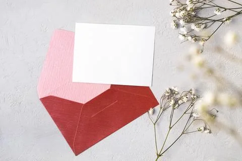 Top view of red envelope, white blank card and gentle flowers on neutral Photos