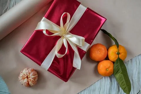 Top View of Red Gift Box with Tangerines on Beige Background Foto stock