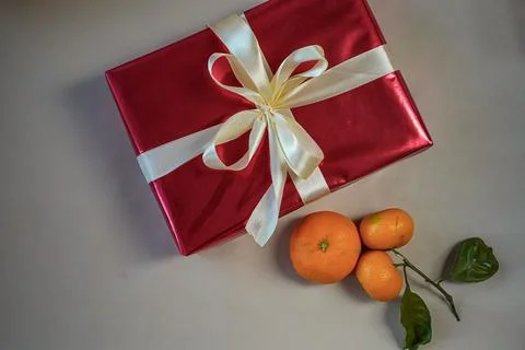 Top View of Red Gift Box with Bow and Tangerines on Beige Background Stock Photos