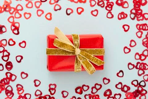 Top view of red gift boxe with golden sparkling ribbon and heart shaped confe Stock-Fotos