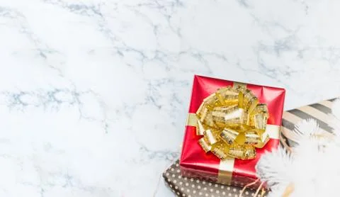 Top view of red glossy present box with golden bow and ribbon lay under white Foto stock