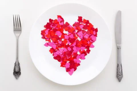 Top view red heart shape on a white plate with silverware. Background for a Stock Photos