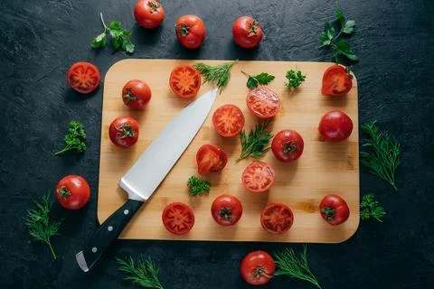 Top view of red sliced tomatoes on wooden chopping board. Sharp knife near... Фото