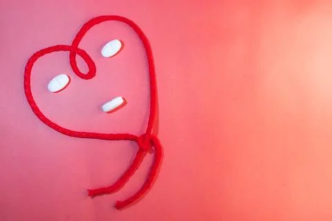 Top view of red string in the shape of a heart simulating a face. Copy space Stock Photos