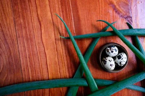 Top view on a red table. on the table are quail eggs and leaves of greens or spr Stock Photos