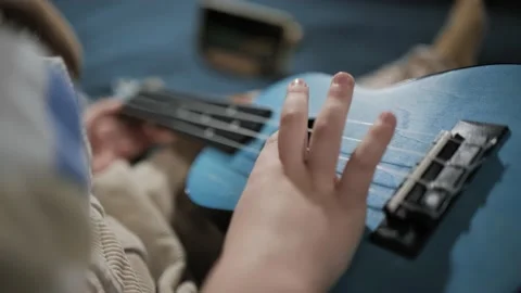 Top view of right hand of small child pulls strings on ukulele. Kid playing 库存影片 238603322