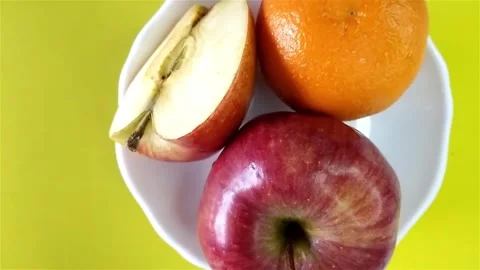 Top view of ripe tasty sliced and whole apple and tangerine on white plate. Stock Footage 280354533