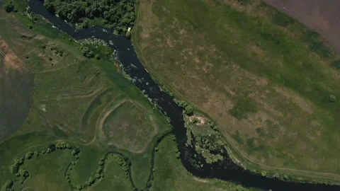 Top view of the river, surrounded by trees and meadows on its banks, view from Stock Footage 109856539