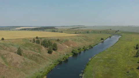 Top view of the river, surrounded by trees and meadows on its banks, view from Stock Footage 111228246