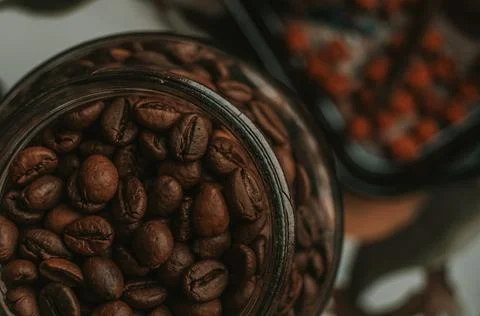 Top view of roasted coffee beans in a glass jar. Horizontal composition, close Stock Photos