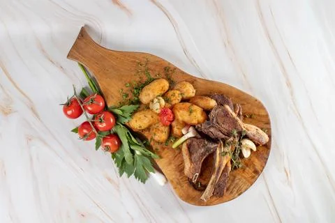 Top view of roasted lamb chops and potatoes on a rustic wooden board, Foto stock