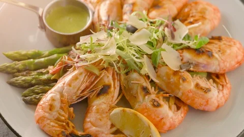 Top view of roasted shrimps served with asparagus and lemon on white plate Stock Footage 102712756