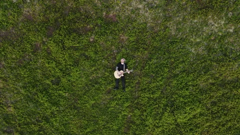 Top View a rock man lying on the ground and playing an acoustic guitar. Playing Stock Footage 194698344