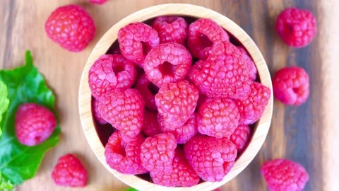 Top view Rotate Red Raspberry fruit in wooden bowl on Wooden background. Stock Footage 235388099