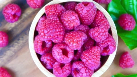 Top view Rotate Red Raspberry fruit in wooden bowl on Wooden background. Stock Footage 235388196