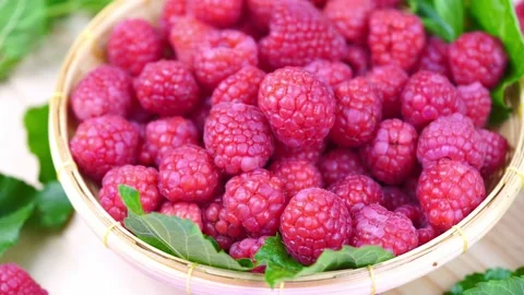 Top view Rotate Red Raspberry fruit in wooden bowl on Wooden background. Stock Footage 235388245