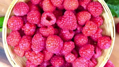 Top view Rotate Red Raspberry fruit in wooden bowl on Wooden background. Stock Footage 235388323