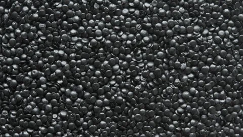 Top view of rotating black polyethylene granules forms dense plastic texture for Stock Footage 334659510