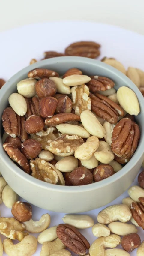 Top view rotating bowl of mixed nuts. Pecans, almonds, walnuts and hazelnuts 库存影片 345654371