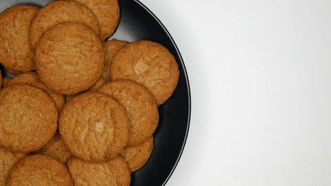 Top View Rotating Close Up Of Fresh Brown Oatmeal Cookies On A Black Plate On A  Stock Footage 128592373
