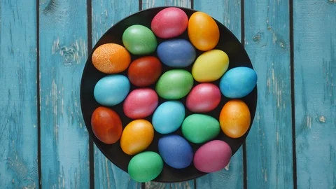 Top View Rotating Of Colorful Easter Eggs Lying On Black Plate On A Blue Wooden  Stock Footage 126545647