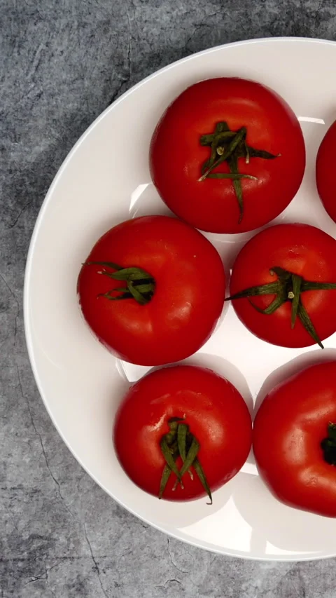 Top View Of Rotating Fresh Red Raw Tomatoes On A White Plate On A Dark Grey Marb Stock Footage 267860766