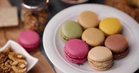 Top view rotating loop of colorful macarons with bagel and walnuts on plate Stock Footage 320165291