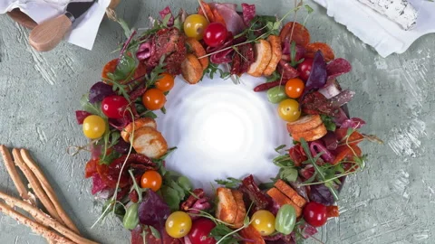 Top view of a round appetizer plate of cheese, sausage and vegetables in the for Stock Footage 304458067