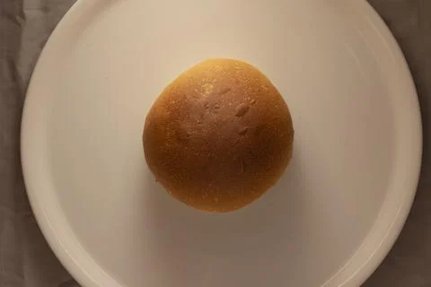 Top view round bread roll on white plate against neutral background Stock Photos