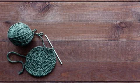 Top view of round crochet patterns on a wooden surface, with a skein of yarn Stock Photos